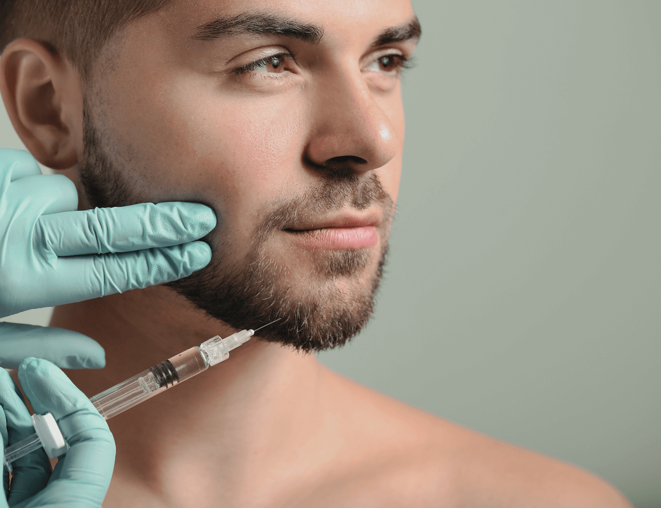 A confident man applying a cotton pad to his face, showcasing self-care and wellness routines.