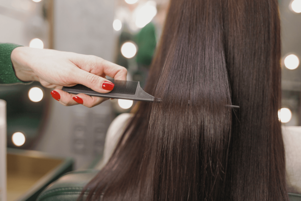 Hairdresser combing smooth, shiny hair after keratin treatment.
