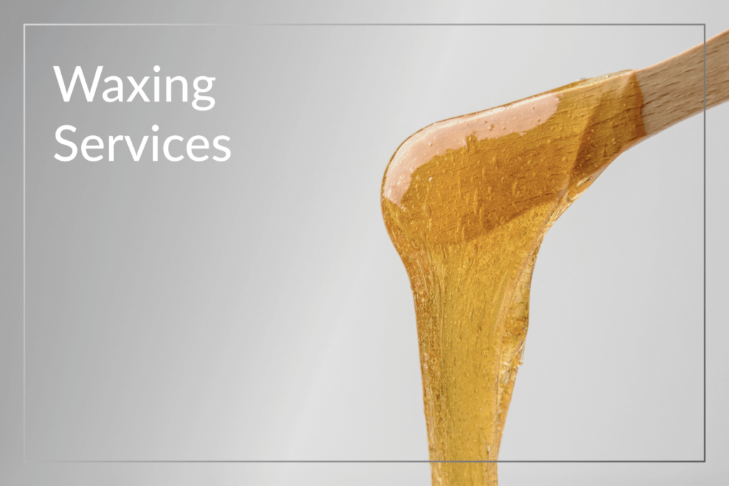 Close-up of warm golden wax on a wooden spatula for waxing services