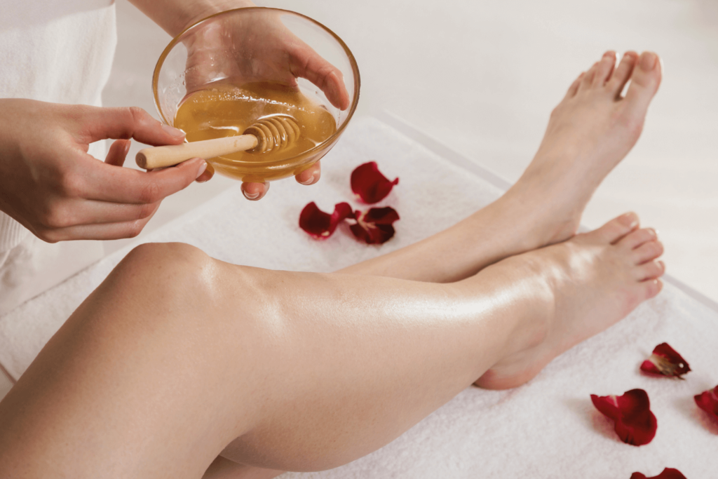 Full legs waxing process with honey wax being applied on a client’s leg.